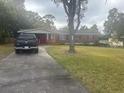 Brick single-story home with a long driveway and lush front yard at 404 E Kentucky Ave, Deland, FL 32724