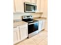 A close up of the kitchen with stainless steel oven and microwave, granite counters and white cabinets at 5216 Greenheart Ave, Mount Dora, FL 32757