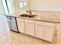 Stylish kitchen island features stainless steel dishwasher, granite counters and white cabinetry at 5216 Greenheart Ave, Mount Dora, FL 32757