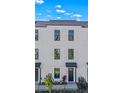 A close-up view of a modern three-story townhome's facade, featuring white siding and black-framed windows at 6678 Juneberry Way, Winter Garden, FL 34787