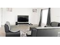 Modern living room showcasing gray furniture, a flat-screen TV, and a plush rug at 707 Staffora St, Haines City, FL 33844