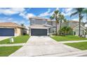 Beautiful gray two-story home with a well-kept lawn, driveway, and tropical palm trees at 726 Lake Biscayne Way, Orlando, FL 32824