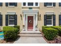 Inviting entrance with a red door, decorative wreath, manicured bushes and stone steps at 754 Centervale Dr, Kissimmee, FL 34747