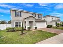 Attractive two-story home with a brick driveway, attached garage, and lush green lawn at 178 Aria Way, Davenport, FL 33837