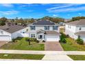 A two-story home featuring solar panels and a brick driveway with a manicured lawn at 178 Aria Way, Davenport, FL 33837