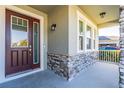 Close-up of a front porch with stone columns, a wood door, and windows, offering curb appeal at 2417 Annacella Ave, Kissimmee, FL 34741