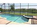 Inviting screened-in pool area with attached jacuzzi and serene water view at 2605 Daulby St, Kissimmee, FL 34747