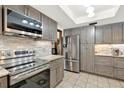Modern kitchen features stainless steel appliances, gray cabinets, and stylish tile backsplash at 28136 Tammi Dr, Tavares, FL 32778