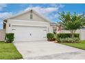 Inviting home featuring a two-car garage, lush green lawn, and tidy landscaping enhancing its appeal at 3945 Angola Ln, Sanford, FL 32771