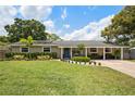 Inviting single-story home with lush green lawn and covered porch, featuring a striking blue front door at 417 Carvell Dr, Winter Park, FL 32792