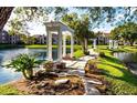 Scenic pond view featuring lush landscaping, stone pathways, and elegant white gazebos at 4225 Thornbriar Ln # 305, Orlando, FL 32822