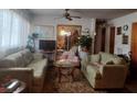 Comfortable living room featuring couches, patterned carpet, ceiling fan and window with sheer curtains at 442 Fanfair Ave, Orlando, FL 32811
