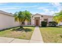 Inviting single-story home featuring palm trees, a well-manicured lawn, and a charming walkway to the front door at 504 Delido Way, Kissimmee, FL 34758