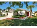 Well-maintained home featuring lush landscaping, palm trees and bright red front door at 1175 Seasons Blvd, Kissimmee, FL 34746
