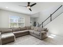 Bright living room with a large gray sectional sofa and staircase with black railing at 13748 Werrington Dr, Winter Garden, FL 34787