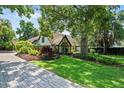 Inviting home exterior showcasing a lush lawn and brick driveway framed by mature trees and landscaping at 1742 Barcelona Way, Winter Park, FL 32789