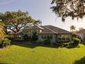 Large backyard with lush green lawn, mature trees, and a view of the home's exterior at 1802 Hartford Path, The Villages, FL 32162