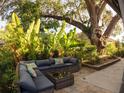 Inviting outdoor patio with comfortable seating, lush landscaping, and shade provided by a mature tree at 1802 Hartford Path, The Villages, FL 32162