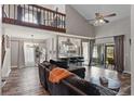 Cozy living room featuring high ceilings, a ceiling fan, a wooden railing, and an adjacent kitchen and dining area at 2239 Meadowmouse St, Orlando, FL 32837