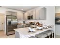 Modern kitchen featuring stainless steel appliances, gray cabinets, and a breakfast bar with seating at 5113 Forget Me Not Ave, Lake Hamilton, FL 33851