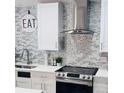 Close-up of the modern kitchen featuring white cabinets, stainless steel appliances, and decorative backsplash at 6216 Beaumont Ave, Orlando, FL 32808