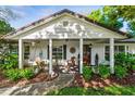 Inviting front porch with mature landscaping, rocking chairs and a white painted brick exterior at 819 E Harbour Ct, Ocoee, FL 34761