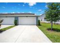 A long driveway leads to the two-car garage, complemented by a green lawn and a young tree at 10940 Leafshore Loop, Orlando, FL 32829