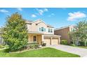 Tan two-story home featuring manicured lawn, two-car garage and traditional architectural details at 1545 Caterpillar St, St Cloud, FL 34771