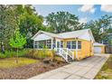 Inviting yellow home with white trim, well-maintained yard, and a private driveway leading to a detached garage at 1624 Park Lake St, Orlando, FL 32803