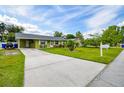 Well-maintained single-story home with long driveway, green lawn, and mature trees in a sunny setting at 206 Montana Ave, St Cloud, FL 34769