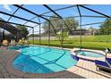 Relaxing screened-in pool and jacuzzi with ample lounge chairs and a beautiful green lawn perfect for outdoor enjoyment at 2624 Daulby St, Kissimmee, FL 34747