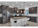 Modern kitchen with stainless steel appliances, dark cabinets, granite countertops, a kitchen island with seating and pendant lights at 3966 Steer Beach Pl, Kissimmee, FL 34746
