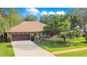 Charming single-story home with a well-manicured lawn, mature trees, and a paved driveway at 477 Eagle Brook Ct, Debary, FL 32713