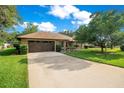 Charming single-story home with a well-manicured lawn, mature trees, and a paved driveway at 477 Eagle Brook Ct, Debary, FL 32713