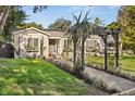 Charming home featuring a well-manicured front yard, a decorative pergola, and beautiful landscaping at 100 Kennison Dr, Orlando, FL 32801