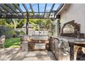 Outdoor kitchen area with stainless steel appliances, stone accents, and a wooden pergola at 100 Kennison Dr, Orlando, FL 32801
