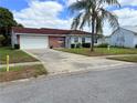 Cozy single-Gathering home with a white garage door, lush lawn, and mature landscaping at 10125 Matchlock Dr, Orlando, FL 32821