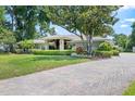 Lovely house with a well-manicured lawn, mature tree, stone accents, brick driveway and lush landscaping at 103 Greenleaf Ln, Altamonte Springs, FL 32714