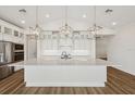 Modern kitchen with sleek white cabinetry, stainless steel appliances, pendant lighting, and an oversized island at 13123 Faro Ct # 23, Winter Garden, FL 34787