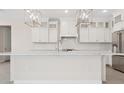 Bright, open kitchen with white cabinetry, stainless steel appliances, a stylish backsplash, and a large center island at 13187 Telsen St # 38, Winter Garden, FL 34787