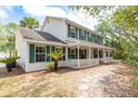 Side view of a two-story home with green shutters, white siding, front porch, and palm trees at 2320 Red Ember Rd, Oviedo, FL 32765