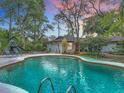 Relaxing backyard features a sparkling in-ground pool with a diving board, a slide and lush greenery at 2350 Worthington Rd, Maitland, FL 32751