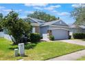 Charming single-story home featuring a two-car garage, stone accents, a well-manicured lawn and landscaping at 3436 Gerber Daisy Ln, Oviedo, FL 32766