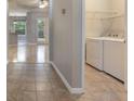 Convenient laundry room featuring a washer and dryer, shelving and tile floors, adjacent to the entry hall at 3436 Gerber Daisy Ln, Oviedo, FL 32766