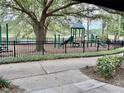 Community playground with green equipment and a lake in the background at 402 Ravenshill Way, Deland, FL 32724
