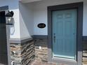 Close-up of the front door featuring a light blue painted door with grey trim, stylish door fixtures, and the house number displayed at 5113 Prairie Preserve Run, St Cloud, FL 34772