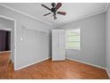 Bedroom with hardwood floors, ceiling fan, white wardrobe, and single window to the exterior at 1010 Timor Ave, Orlando, FL 32804