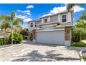 Charming house showcasing a front yard with palm trees and a two-car garage with brick and stone accents at 10142 Hidden Dunes Ln, Orlando, FL 32832