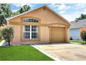 Charming one-story home with tan stucco, arched window, tan garage door, and green lawn at 107 Pamala Ct, Sanford, FL 32771