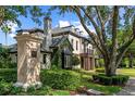 Beautiful home exterior with stone pillar, lush landscaping, and mature trees at 141 S Phelps Ave, Winter Park, FL 32789